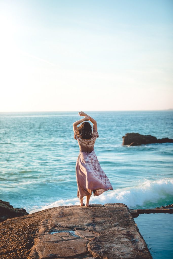 Woman stretching on a rock on the beach