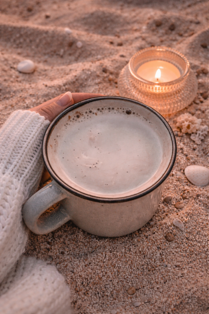 cappuccino in a mug and a candle on the beach