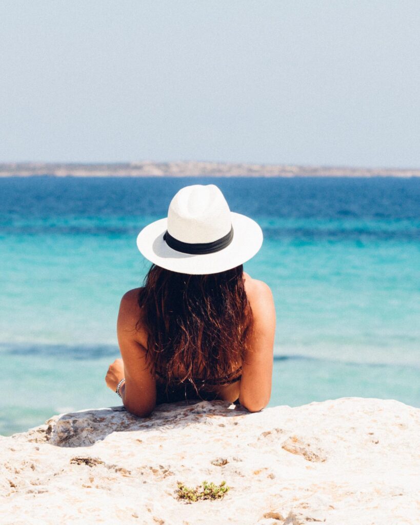 Woman in a star hat leans back in the sand