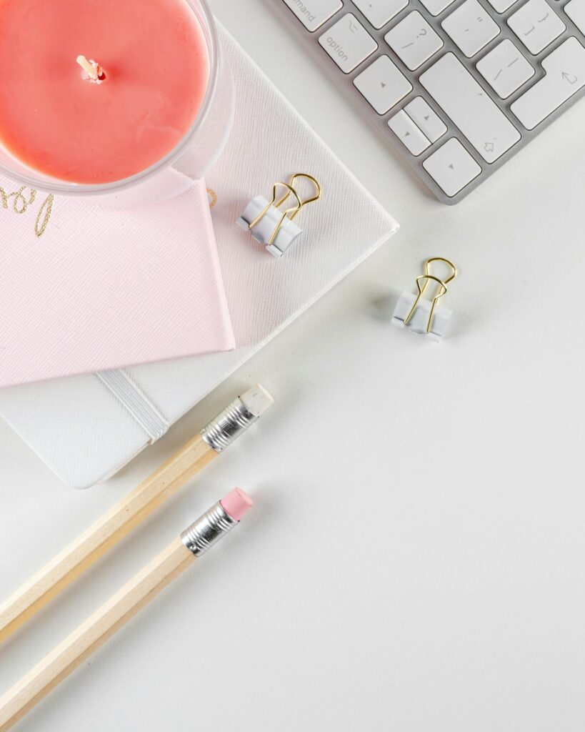 paper clips, pencil, candle and keyboard sitting on a white desk