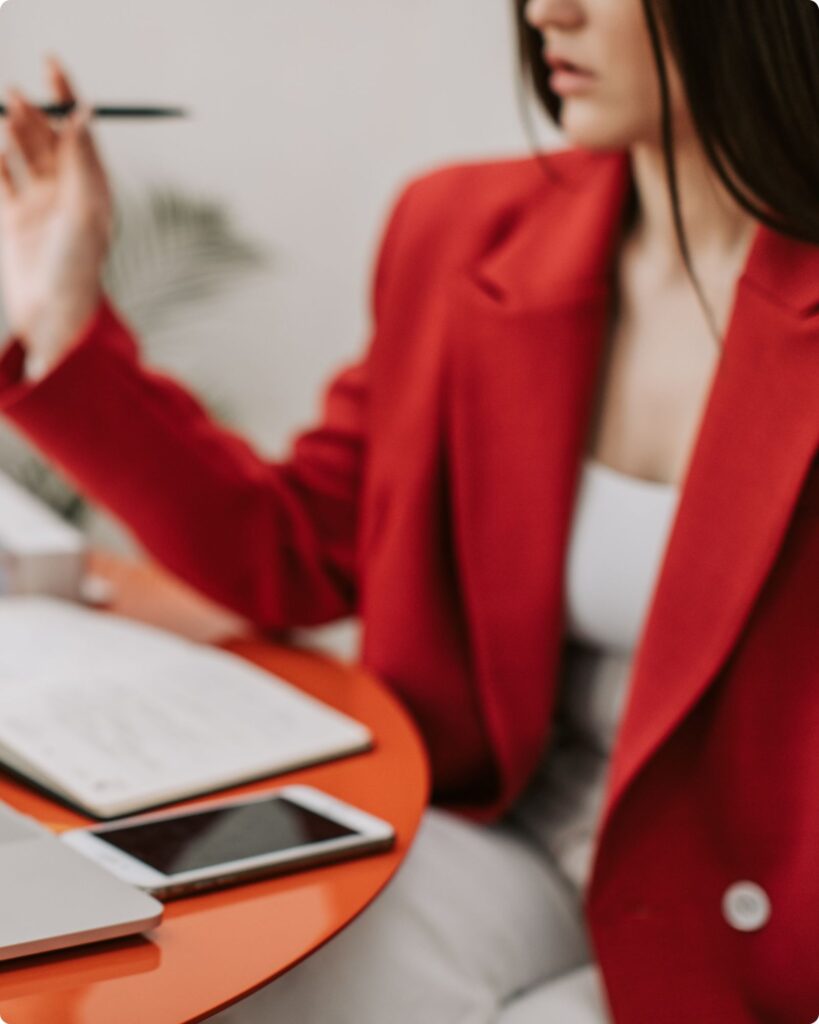 Woman in red blazer sits at table and works