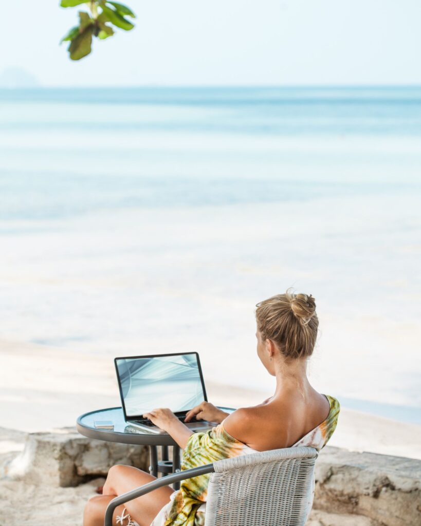 Woman working on a laptop sitting on the beach