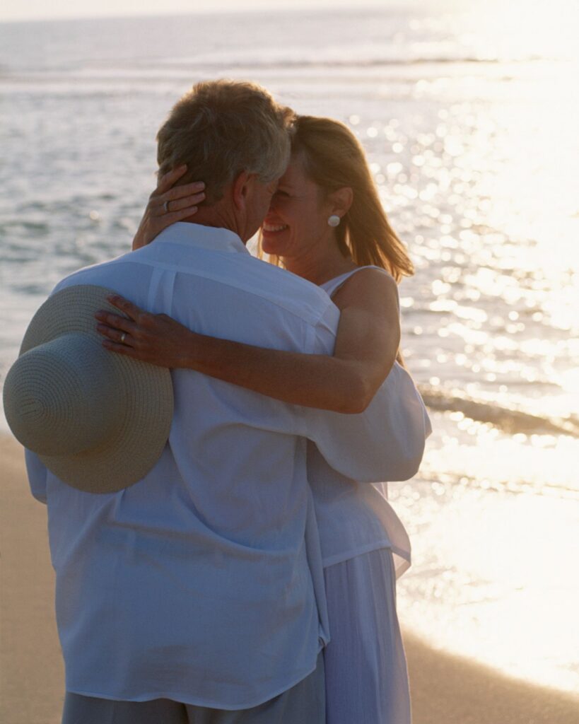 Man and woman embrace and look into each others eyes on the beach