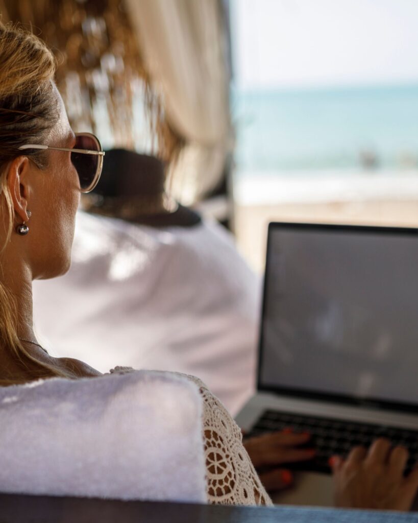 Woman working on laptop under a cabana on the beach